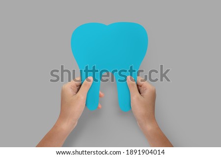 Hands holding blue tooth isolated.  Teeth care and protection concept. 