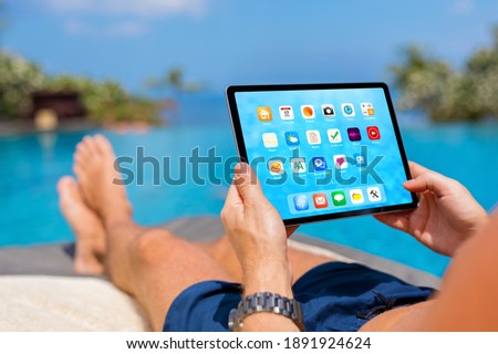 Man using tablet computer while relaxing by the pool