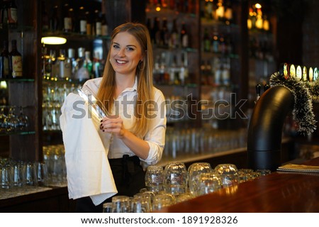 Portrait of happy woman who works as a bartender at bar. Royalty-Free Stock Photo #1891928326