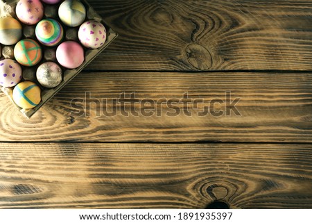 Easter eggs on a stand on wooden background with place for text, top view.