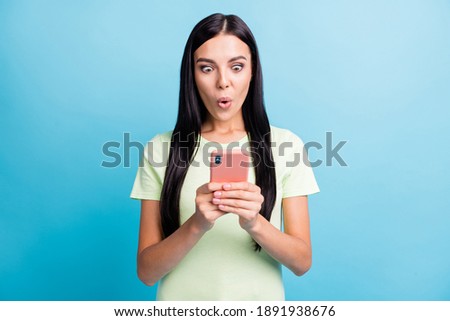 Photo portrait of stunned woman holding phone in two hands isolated on pastel blue colored background