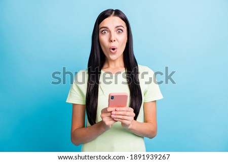 Photo portrait of astonished woman holding phone in two hands isolated on pastel blue colored background