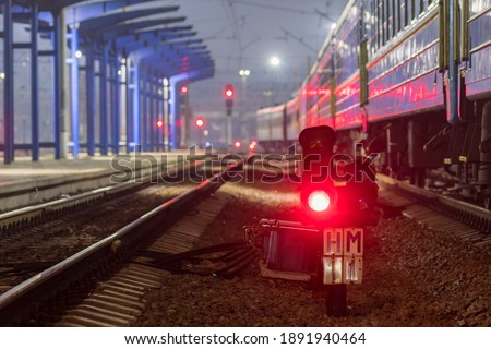 The red light of the traffic light signals a redirection signal for trains.  Train Station.  Night photo.
