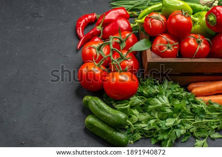 Close up view of vegetable basket with a bunch of green and peppers cucumber and tomatoes with stem carrots beets on dark background stock photo