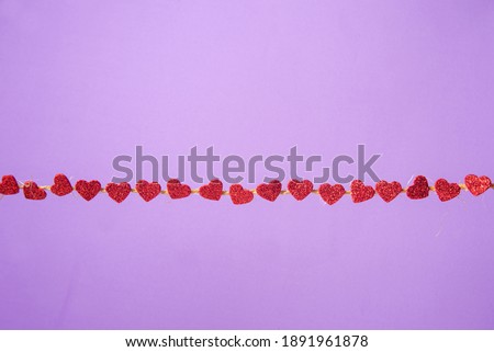 Hearts, clothesline of red hearts on lilac background, selective focus, top view.
