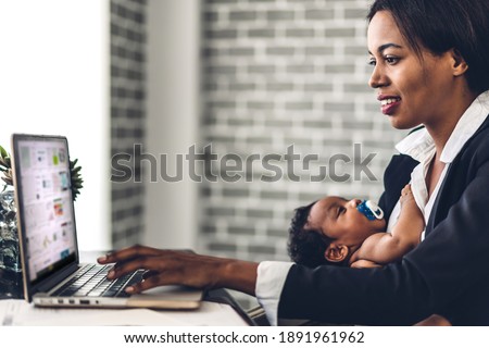 Portrait of african american black mother relaxing using technology of laptop computer with black baby while sitting on table.Young creative african woman working at home.work from home concept