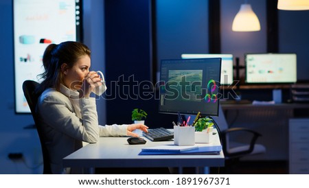 Freelancer content creator working overtime to respect deadline sitting at desk in start-up business office. Woman videographer editing audio film montage on professional laptop at midnight.
