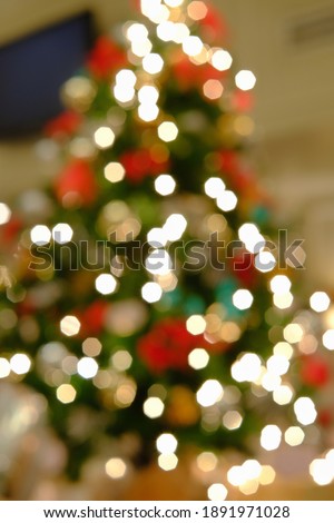 An out of focus picture of a Christmas tree, decorated with colorful ornaments and lights with beautiful round bokeh. 