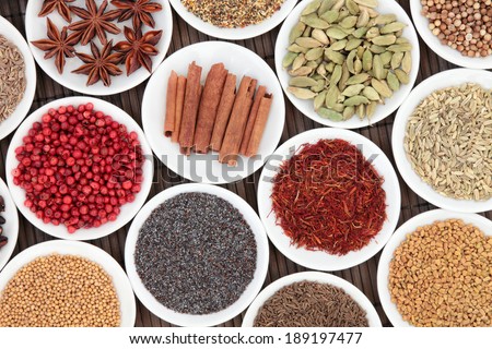 Spice and herb selection in china bowls over bamboo background.