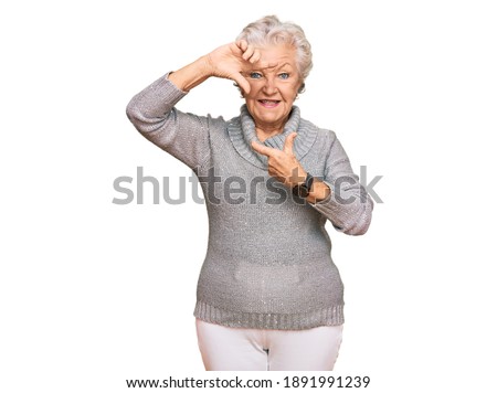 Senior grey-haired woman wearing casual winter sweater smiling making frame with hands and fingers with happy face. creativity and photography concept. 