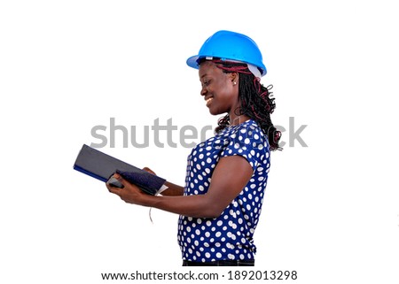 portrait of a beautiful young female construction engineer reading the notes in the note book while smiling.