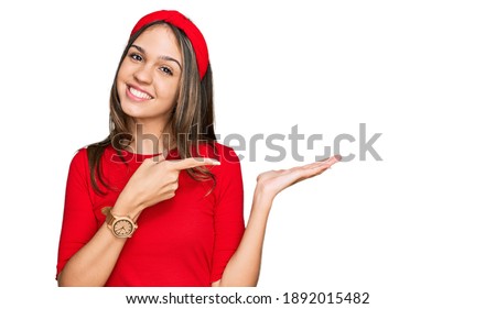 Young brunette woman wearing casual clothes amazed and smiling to the camera while presenting with hand and pointing with finger. 