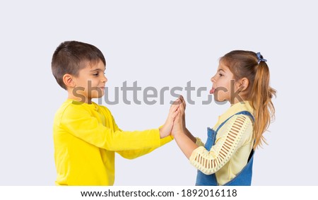 Children have fun. The girl shows her tongue to the boy. White background. The concept of emotions and the time spent by children.