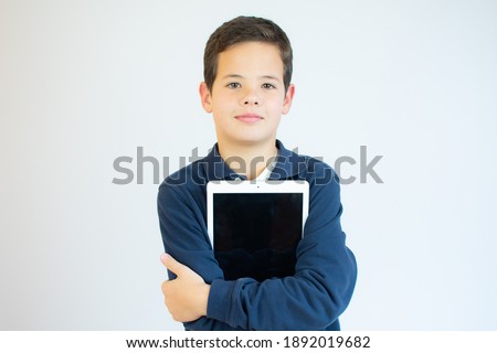 Portrait of a cute smiling boy using a tablet computer against a white background.
