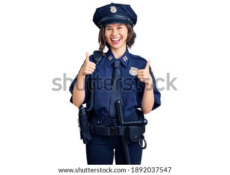Young beautiful girl wearing police uniform success sign doing positive gesture with hand, thumbs up smiling and happy. cheerful expression and winner gesture. 