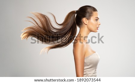 Profile portrait of a beautiful woman with a long  hair. Young  brunette model with  beautiful hair - isolated on white background. Young girl with straight hair flying in the wind.  