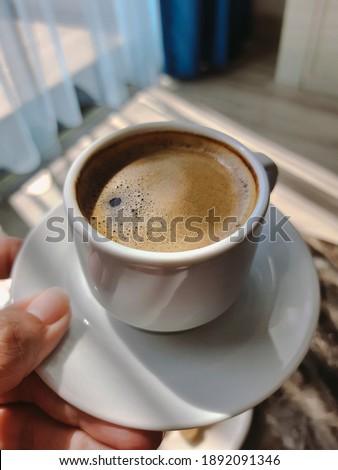 Mobile point of view image of female hand holding cup of coffee and taking pictures of her morning breakfast to share photos on social media resources