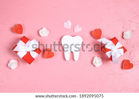 White tooth with gifts, hearts and roses on a pink background. Dental Valentine card. Valentine's day concept.   Royalty-Free Stock Photo #1892095075