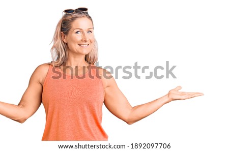 Middle age fit blonde woman wearing casual summer clothes and sunglasses smiling showing both hands open palms, presenting and advertising comparison and balance 