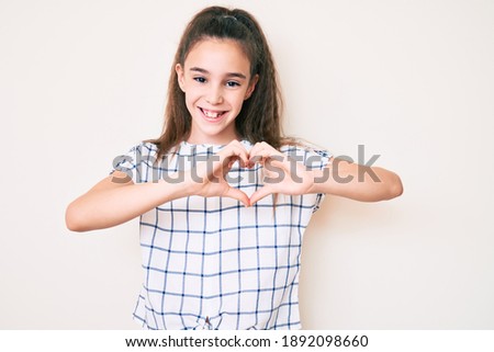 Cute hispanic child girl wearing casual clothes smiling in love showing heart symbol and shape with hands. romantic concept. 