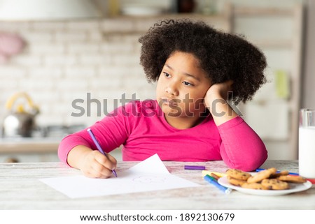 Bored Little African American Girl Drawing At Table In Kitchen, Lonely Black Female Kid Sitting With Upset Face Expression And Looking Away, Pensive Child Resting Head On Hand, Closeup Shot