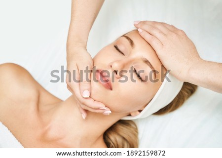 Face massage at spa salon. Doctor hands. Pretty female patient. Beauty treatment. Healthy skin procedure. Young woman head. Light background. Scrub rejuvenation. Facial dermatology mask. Detox therapy Royalty-Free Stock Photo #1892159872