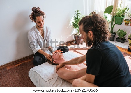 Stock photo of relaxed man enjoying neck massage while lying in a towel.