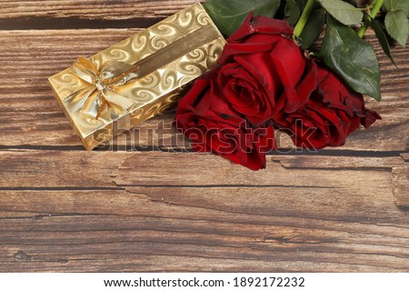 Top view of Red roses with yellow gift box against wooden background. Love symbol. Valentine Day in February. 