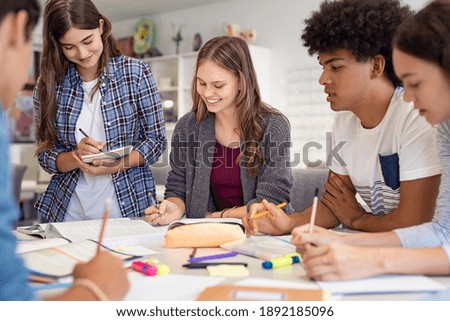 Happy team of high school girls and guys studying together. Group of multiethnic classmates smiling in university library. Group of young people sitting at table working on school assignment. Royalty-Free Stock Photo #1892185096