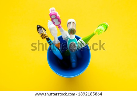 Toothbrushes in a cup on a yellow background. Health care, dental hygiene. Space for text. Top view.