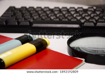 keyboard, green notepad, magnifier, markers lie on a white background. High quality photo
