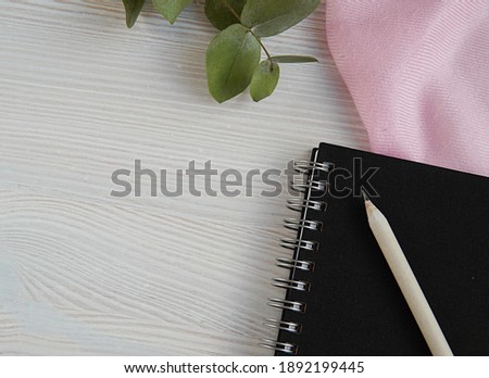 Black spiral notebook planner with pencil, pink scarf, eucalyptus, empty space for text, styled stock photo for blog post, planning, education concept, flat lay.