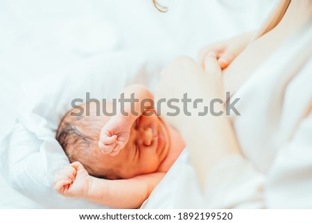 A young mother with newborn child boy in the hospital. Mom and son first time together. Close up portrait.