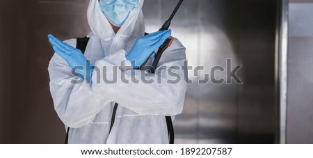 Man in hand cross stop sign with virus protective PPE suit and mask spraying alcohol cleaning covid19 infected area, Virus disinfection concept