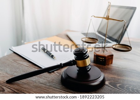 Business and lawyers discussing contract papers with brass scale on desk in office. Law, legal services, advice, justice and law concept picture with film grain effect Royalty-Free Stock Photo #1892223205