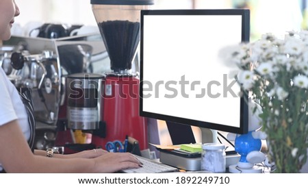 Close up view of barista waitress using computer on counter bar to check stock in coffee shop.