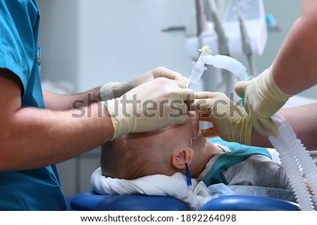 A breathing tube is inserted into the boy. Preparing for surgery. The child is under anesthesia. Treatment of multiple caries. Operation in the dental clinic.