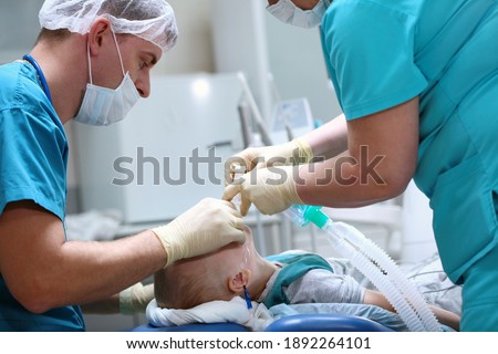 The child is under anesthesia. A breathing tube is inserted into the trachea. Preparing for surgery. Treatment of multiple caries. Operation in the dental clinic.
