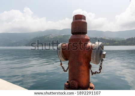 Close-up view of a red metal fire hydrant on the dock by the sea