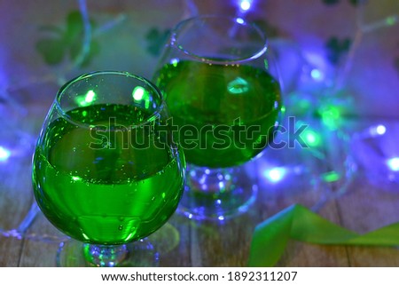 St.Patrick's day background with four-leaf clover. Glass with gerrn beer. Copy space. Neon Garland. 