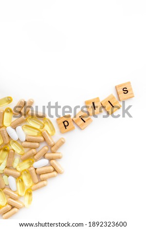 inscription PILLS in wooden cubes on a white background of different pills