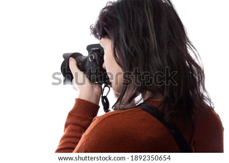 Side view of a female photographer holding a camera isolated on a white background for composites.  The model is posed to face a scenery or copy space