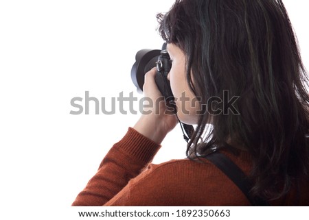 Side view of a female photographer holding a camera isolated on a white background for composites.  The model is posed to face a scenery or copy space