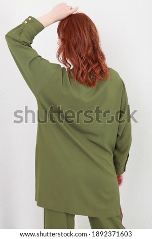 Back side cropped shot of unrecognizable ginger model in trendy clothes, wearing green spring summer suit with stripes and posing over white walls background. High key image. Fashion close up details
