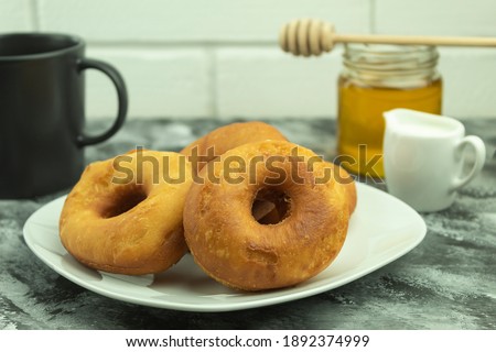 Freshly baked donuts with powdered sugar and honey with coffee. Powdered donuts and coffee with honey with space for text.