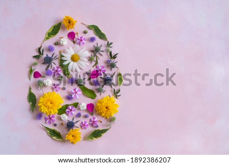 Easter egg shape made of colorful spring flowers and green leaves. Minimal holiday concept. Royalty-Free Stock Photo #1892386207