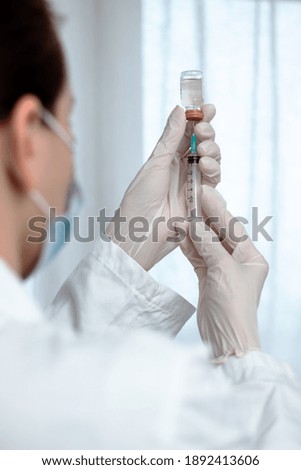 Female doctor or nurse preparing a vaccine shot. Mass vaccination against Coronavirus. Selective focus on a syringe.
