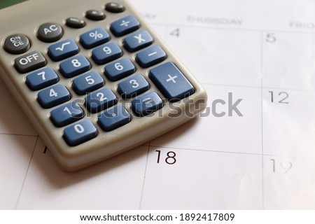 Calculator on top of calendar. Finance concept.