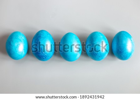 Row of five blue Easter eggs on grey background