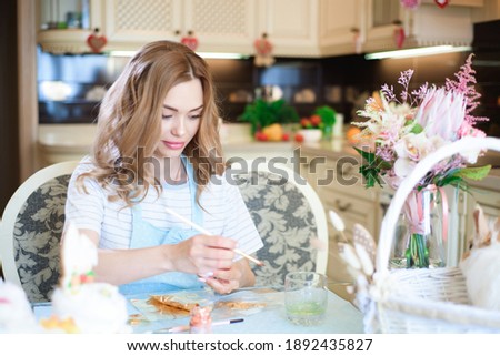 Beautiful girl painting eggs, preparing for Easter